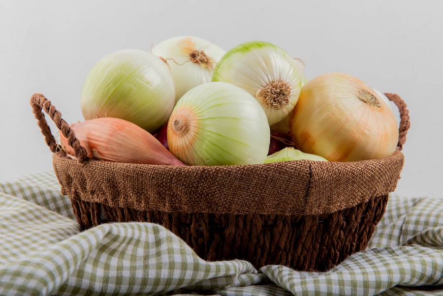 side-view-of-onions-in-basket-on-plaid-cloth-on-white-background.jpg