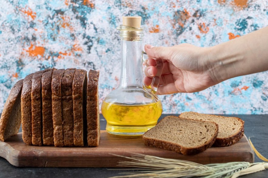 woman-holding-oil-bottle-on-marble-table-with-bread-slices.jpg